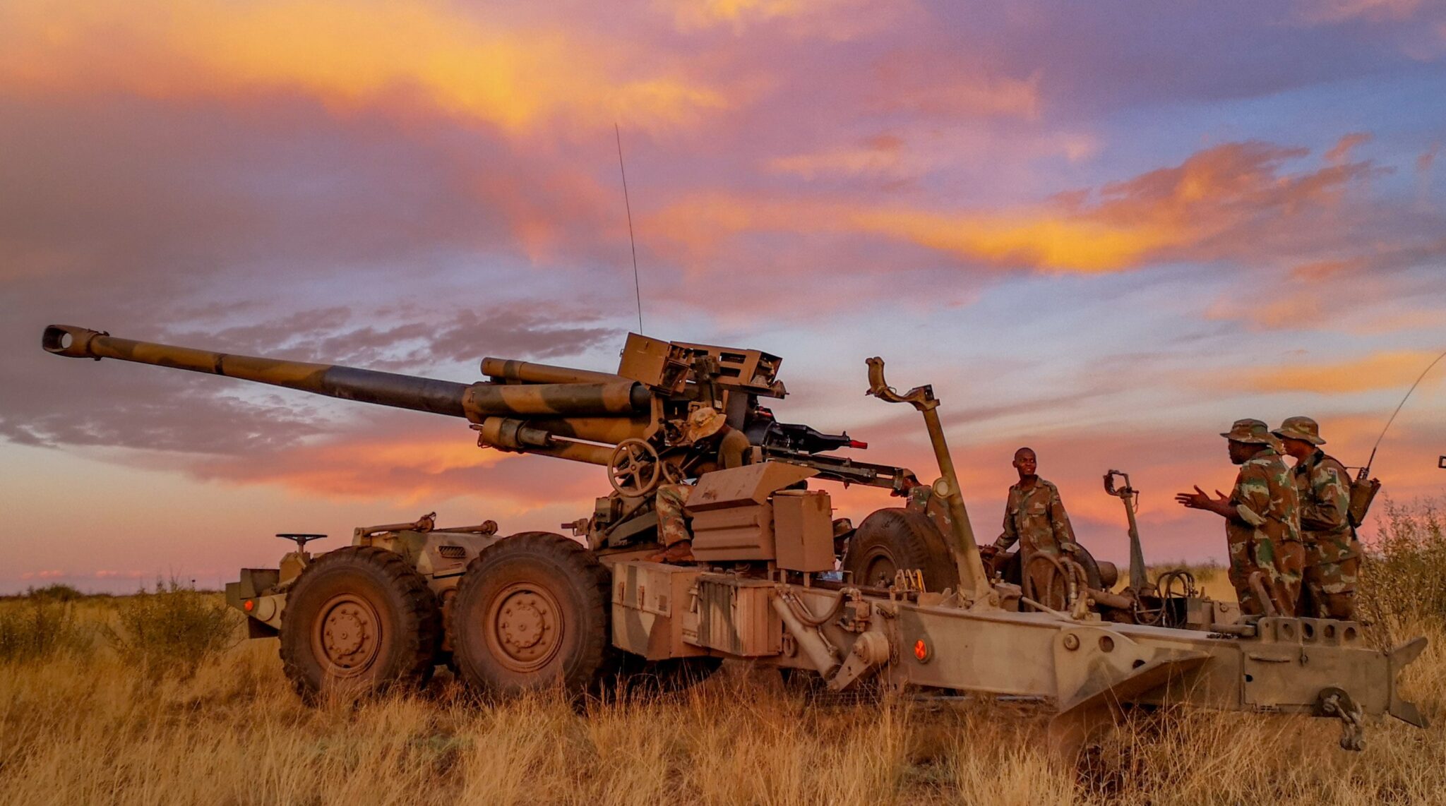South African artillery system and crew during a field exercise at sunset